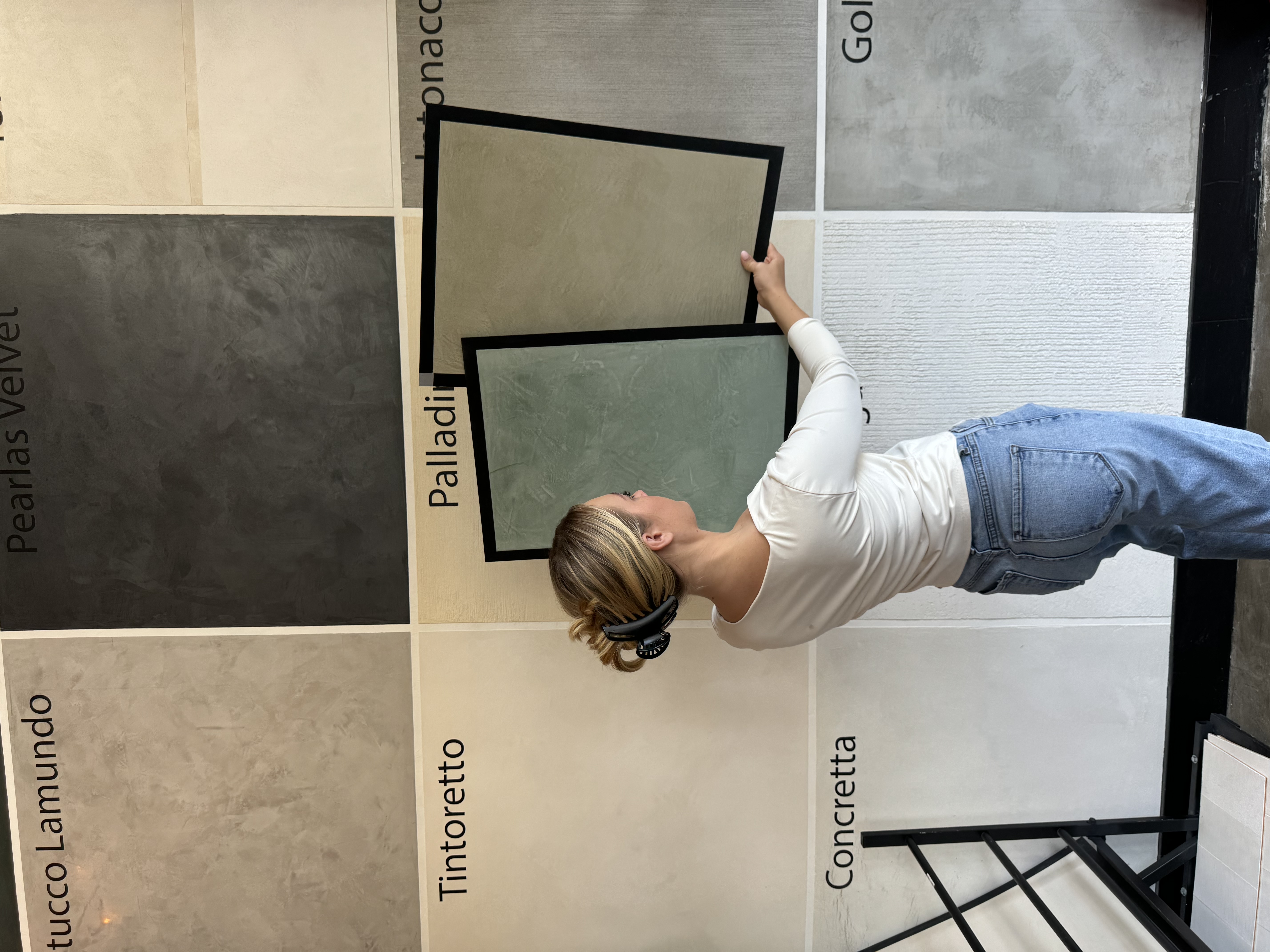 Student exploring different plaster finish samples on display wall