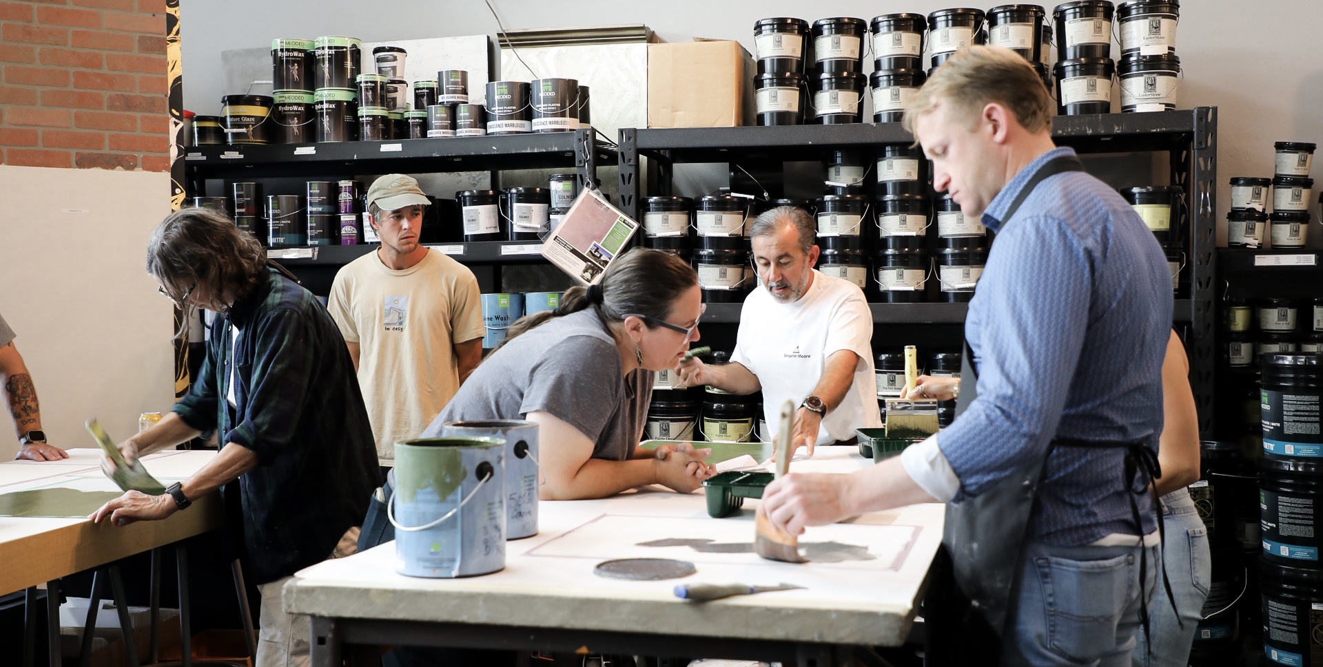 Students learning plaster application techniques in our showroom with instructor guidance